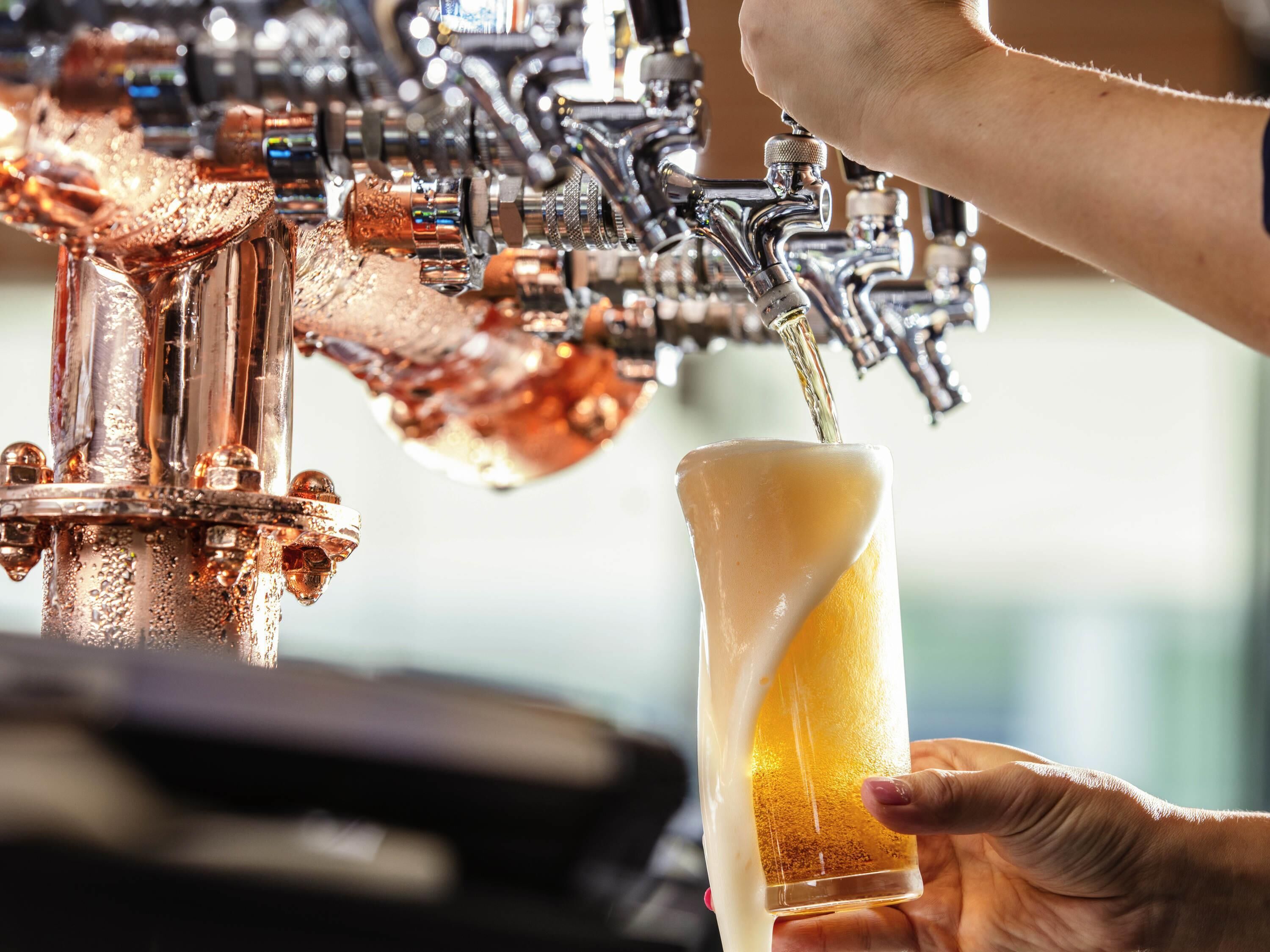 Un robinet qui verse de la bière dans un verre tenu par une personne.