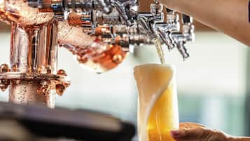 Un robinet qui verse de la bière dans un verre tenu par une personne.