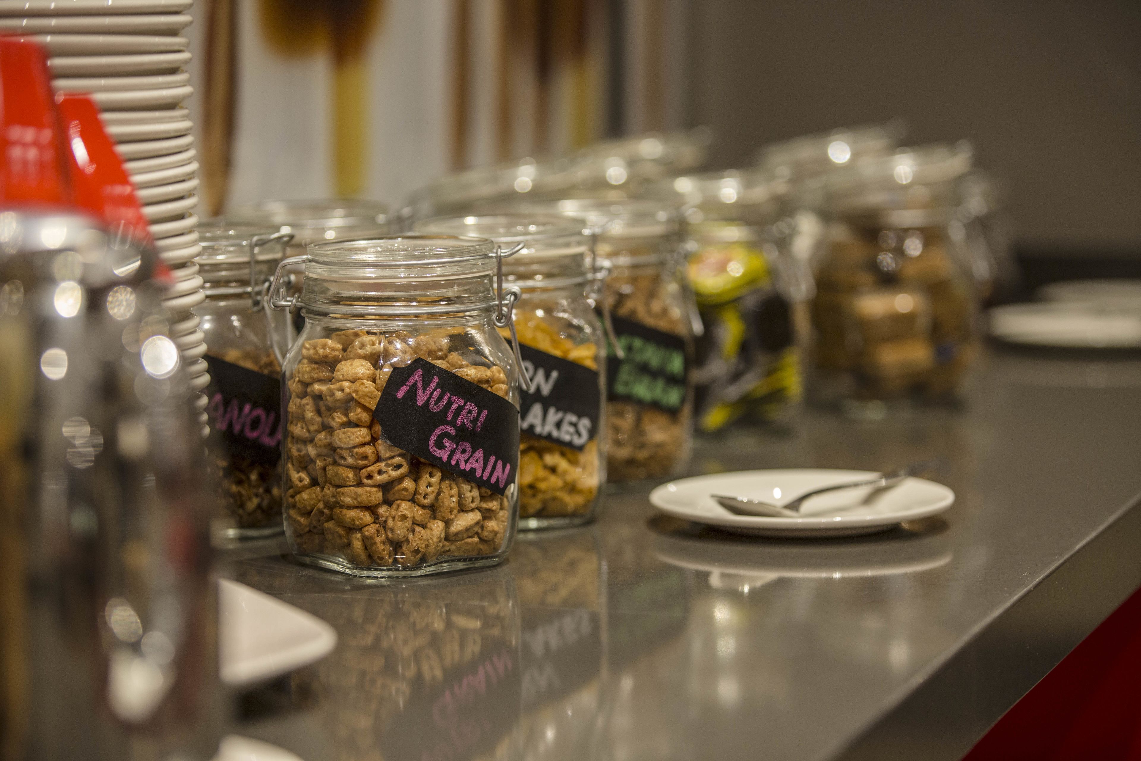 A buffet table with jars labeled "Nutri Grain" and "Protein Cakes."