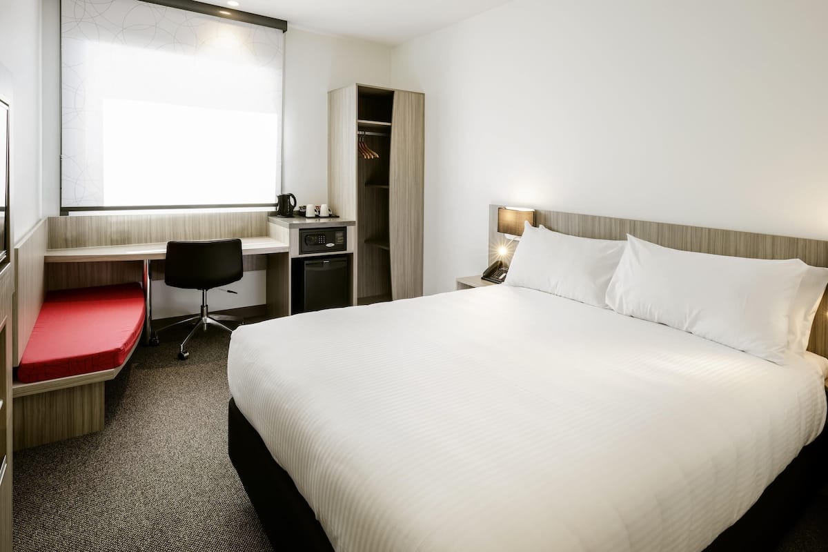 Une chambre d’hôtel équipée d’un lit, d’un bureau, d’une chaise et d’une armoire.