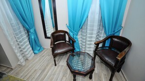 A room with two wooden chairs, a glass table, and curtains. - Dream Hotel (Tirana)