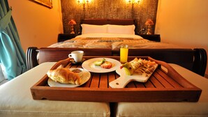 A hotel room with a bed, a bedside table with a tray of breakfast including croissants, a plate with eggs and tomatoes, and a glass of orange juice. - Dream Hotel (Tirana)
