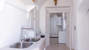 Un pasillo estrecho con paredes y puertas blancas que dan a una zona de cocina.