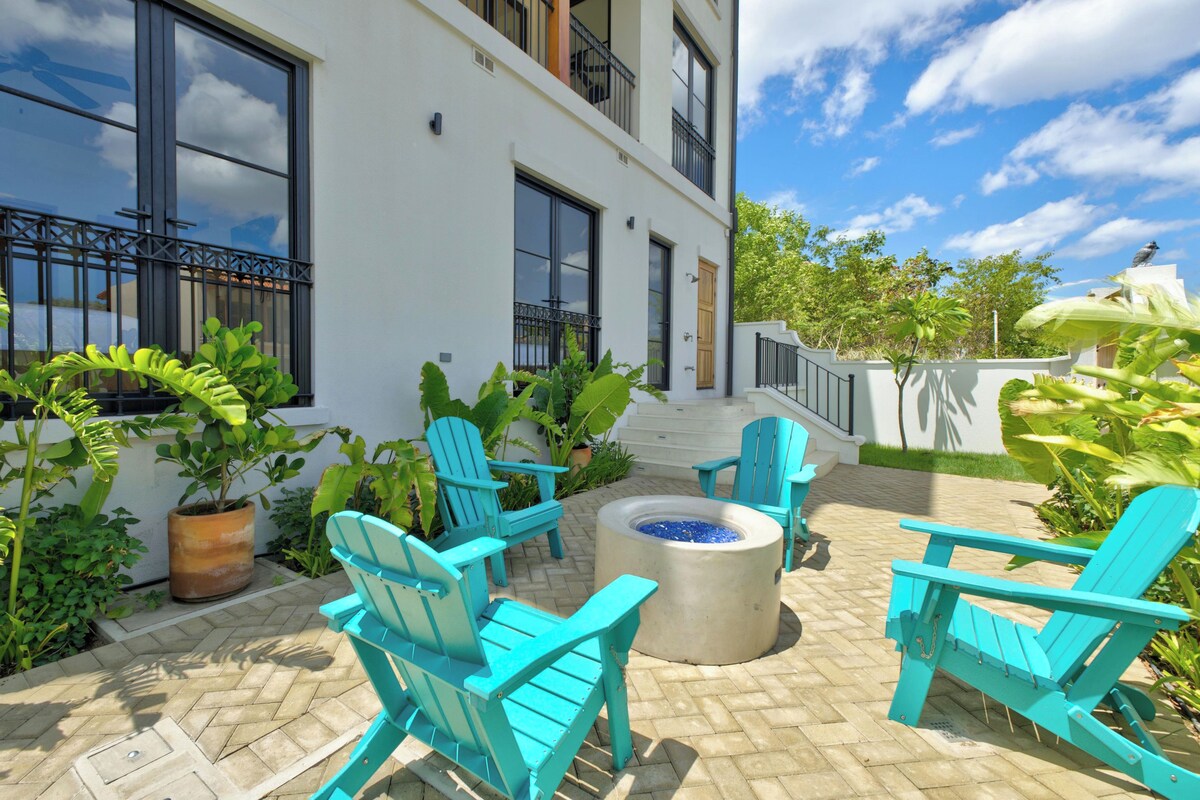 A patio area with turquoise chairs, a fire pit, and potted plants.