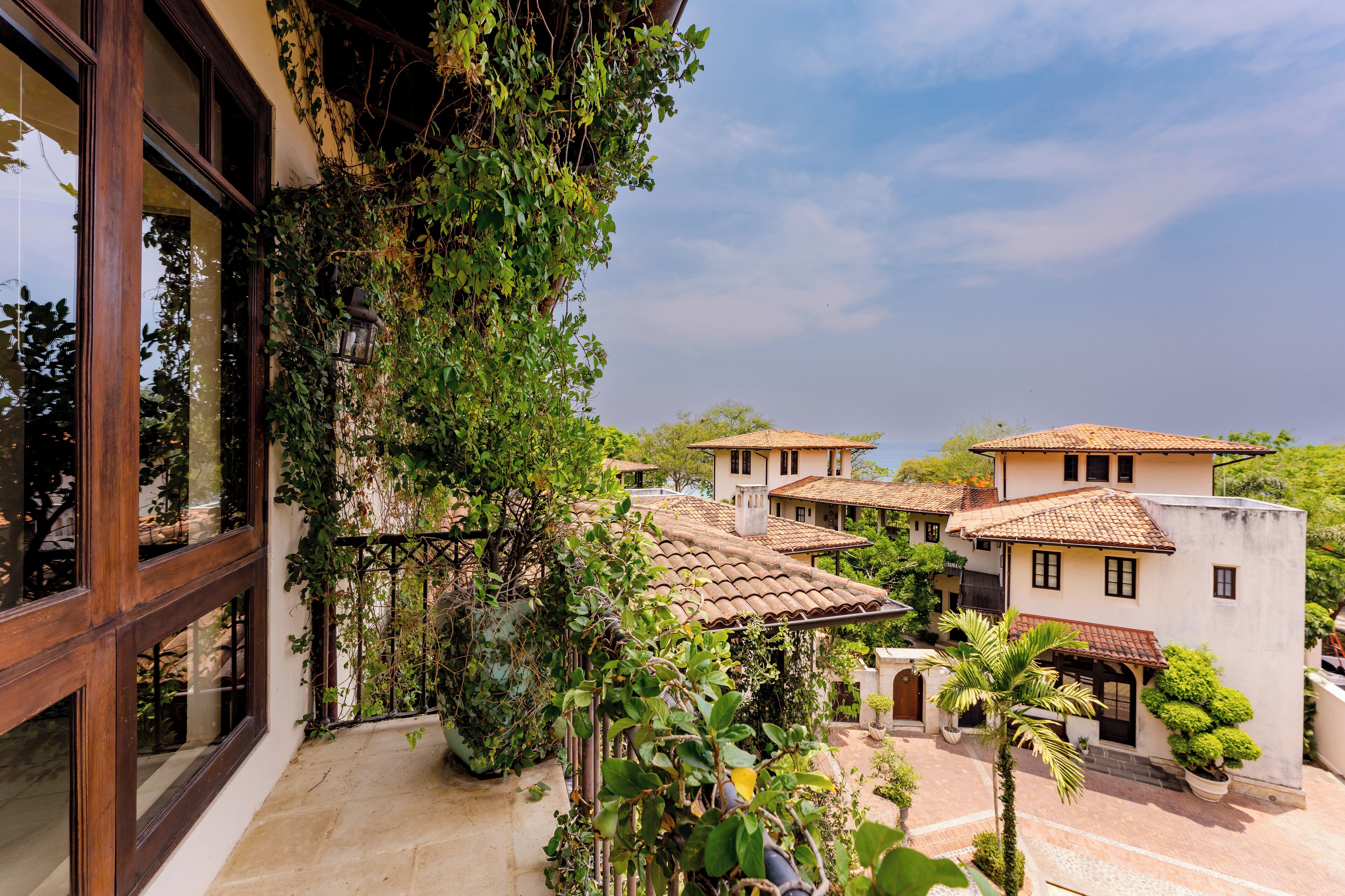 Un patio con vistas a edificios tradicionales, una pérgola de madera y plantas en macetas.
