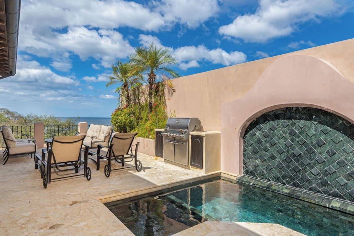Zona de piscina exterior con una parrilla y asientos.