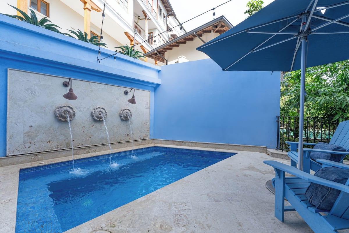Una piscina con pared azul y un elemento acuático.