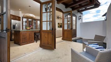 A spacious kitchen with wooden cabinets and a large island, a dining area with wicker furniture, and a view of a swimming pool.