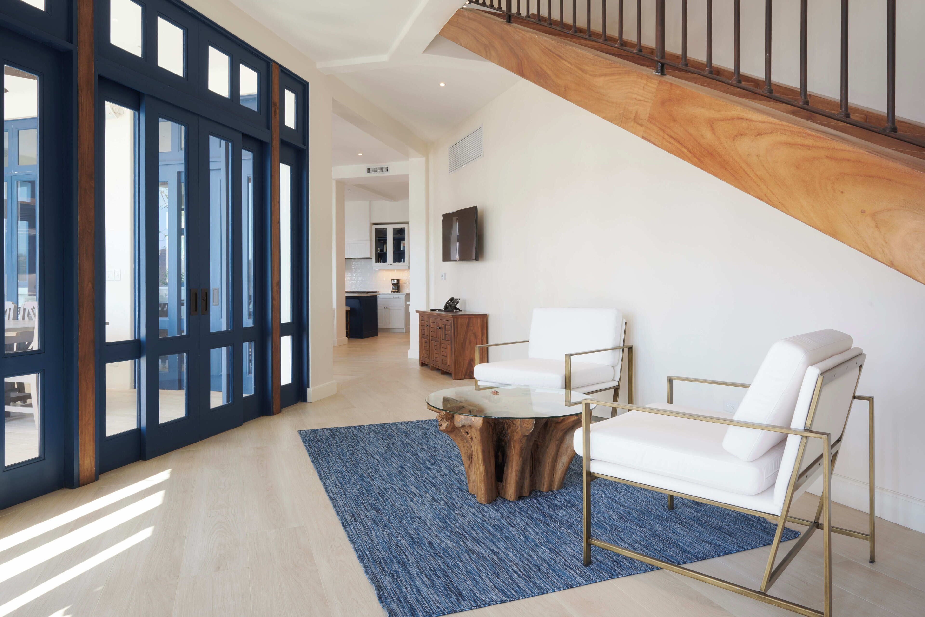 A spacious living area with a staircase, a wooden coffee table, and white sofas.