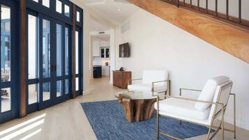 A spacious living area with a staircase, a wooden coffee table, and white sofas.