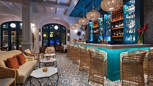 A bar area with wicker furniture, a tiled floor, and a bar stocked with bottles. - Las Catalinas Doorway (Tempate)