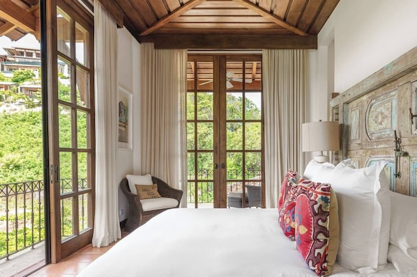 Une chambre avec un grand lit, une chaise et une vue sur la verdure.