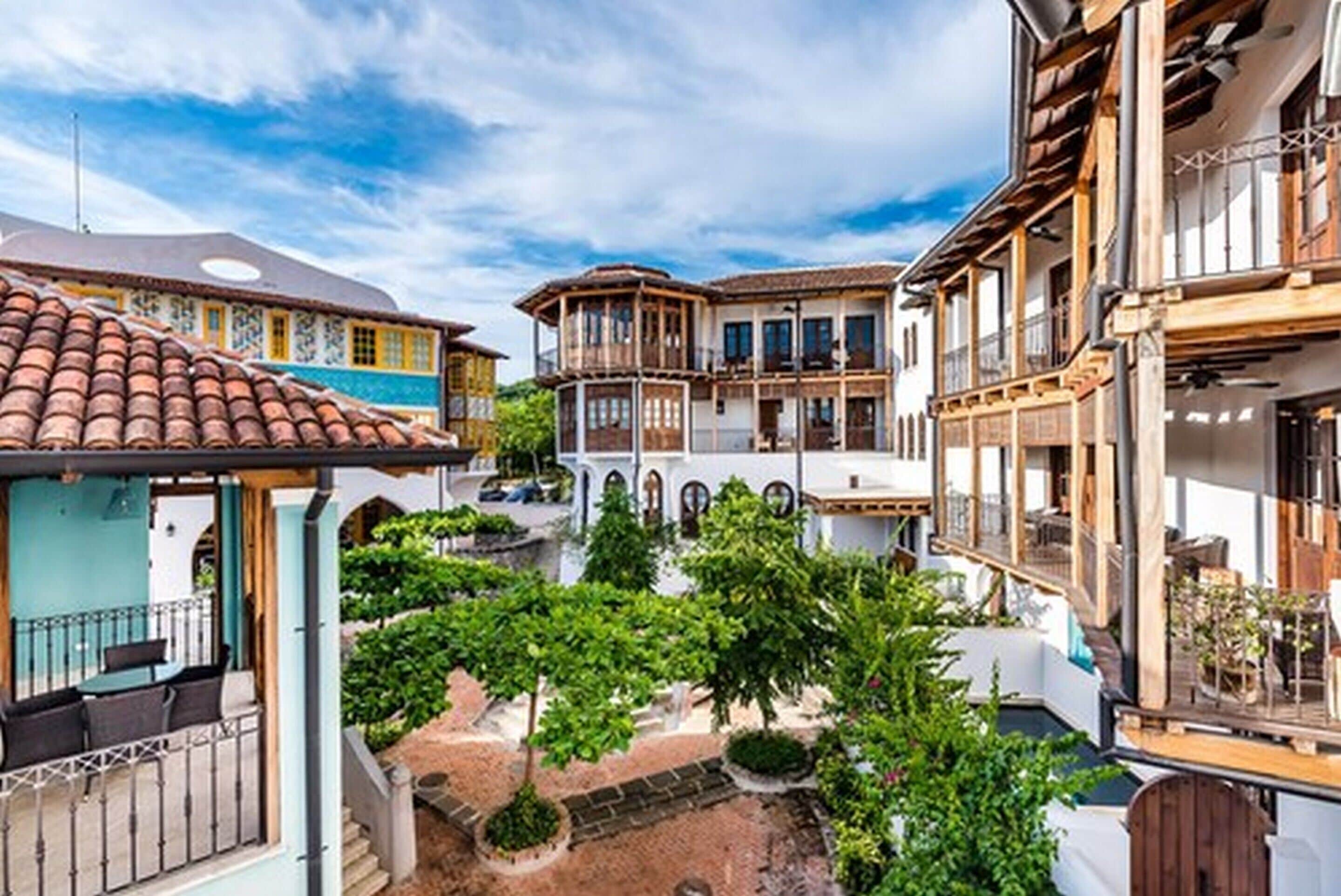 A courtyard with traditional architecture, including a building with a tiled roof and another with wooden balconies.