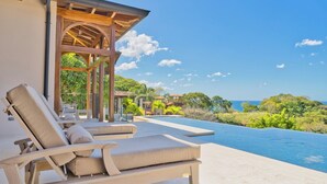 A poolside area with lounge chairs and a view of the ocean. - Las Catalinas Doorway (Tempate)