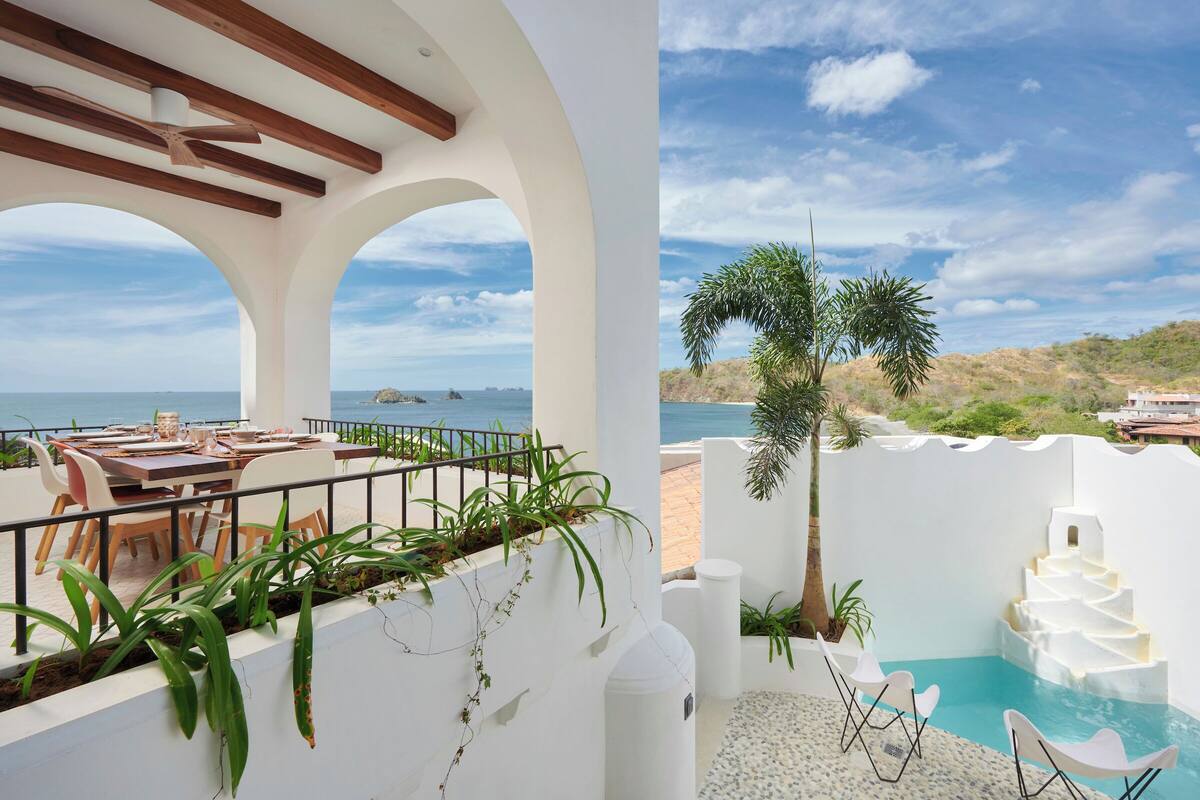 Una terraza con zona de comedor, piscina y vista al mar.