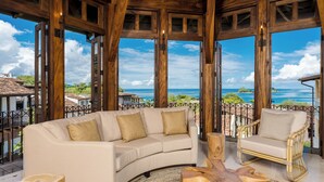 A spacious living area with a beige sofa, a wooden coffee table, and a wicker chair, overlooking a scenic ocean view. - Las Catalinas Doorway (Tempate)