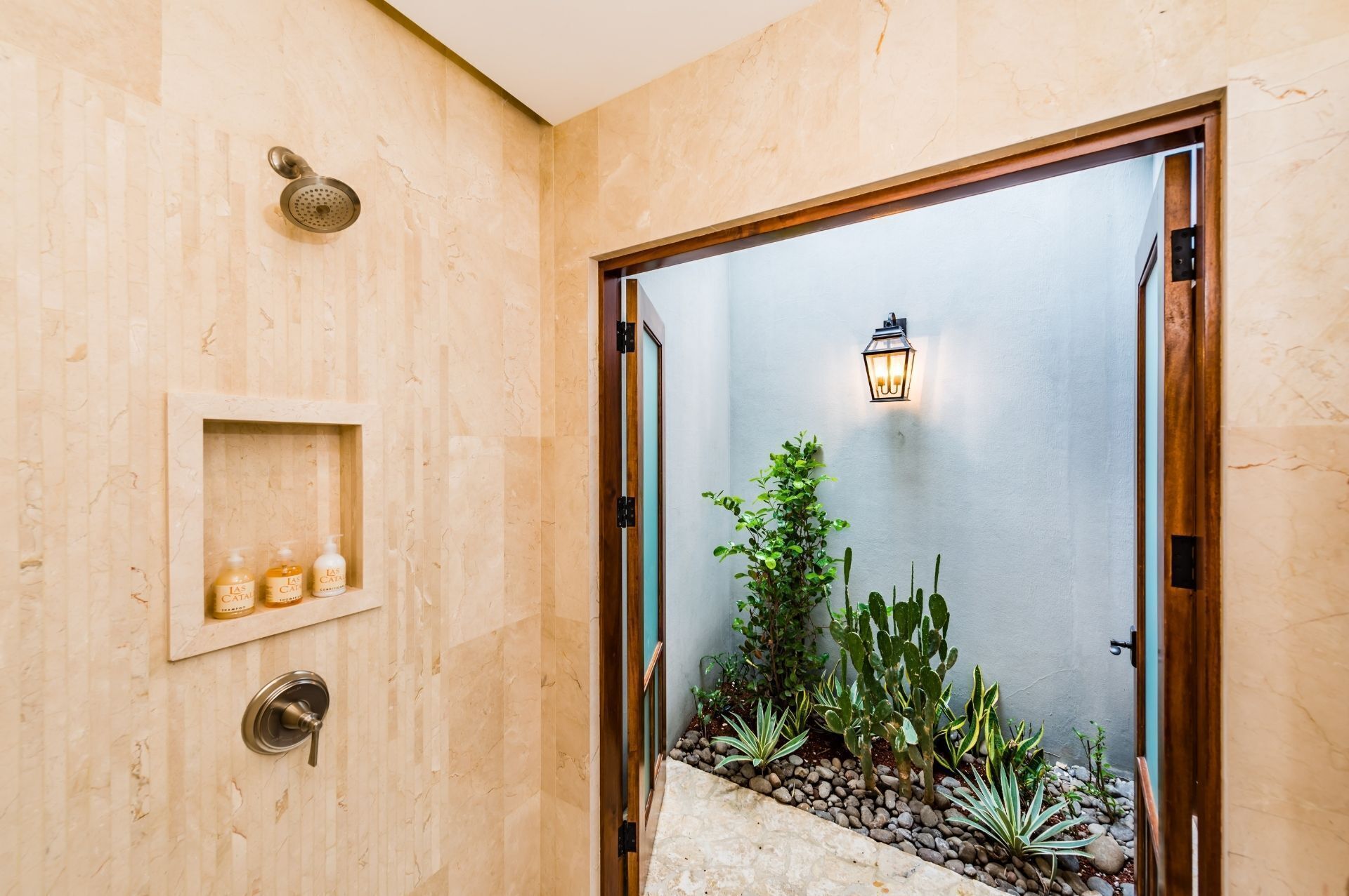A bathroom with a shower, a wall-mounted shelf with toiletries, and a potted plant area.