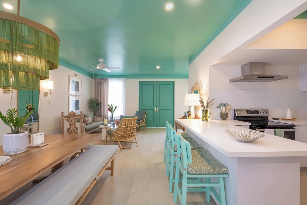 Una cocina moderna con techo color turquesa, encimeras blancas y una isla central.