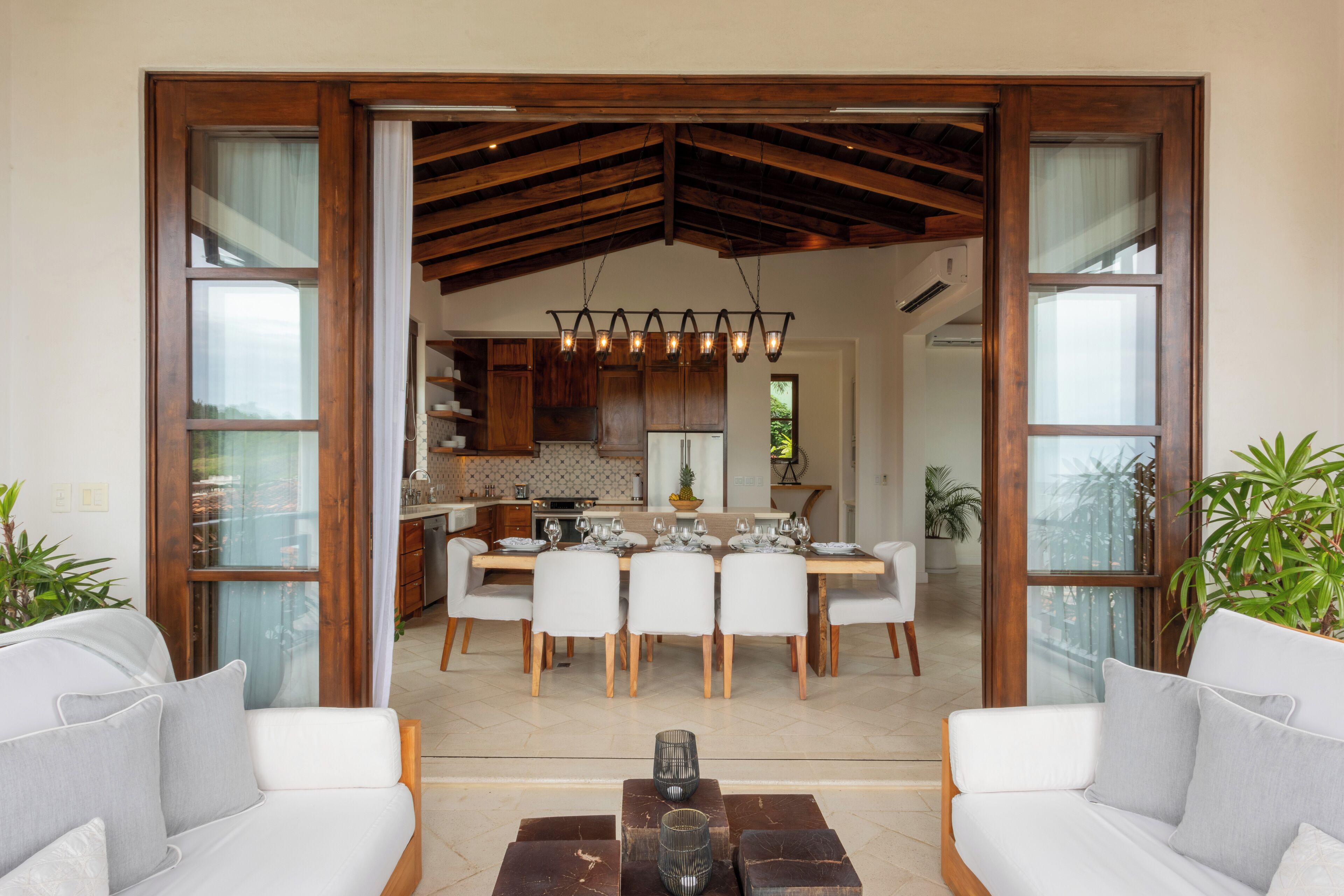 A spacious living area with a dining table set for six, surrounded by white sofas and a coffee table.