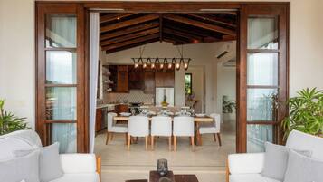 A spacious living area with a dining table set for six, surrounded by white sofas and a coffee table.