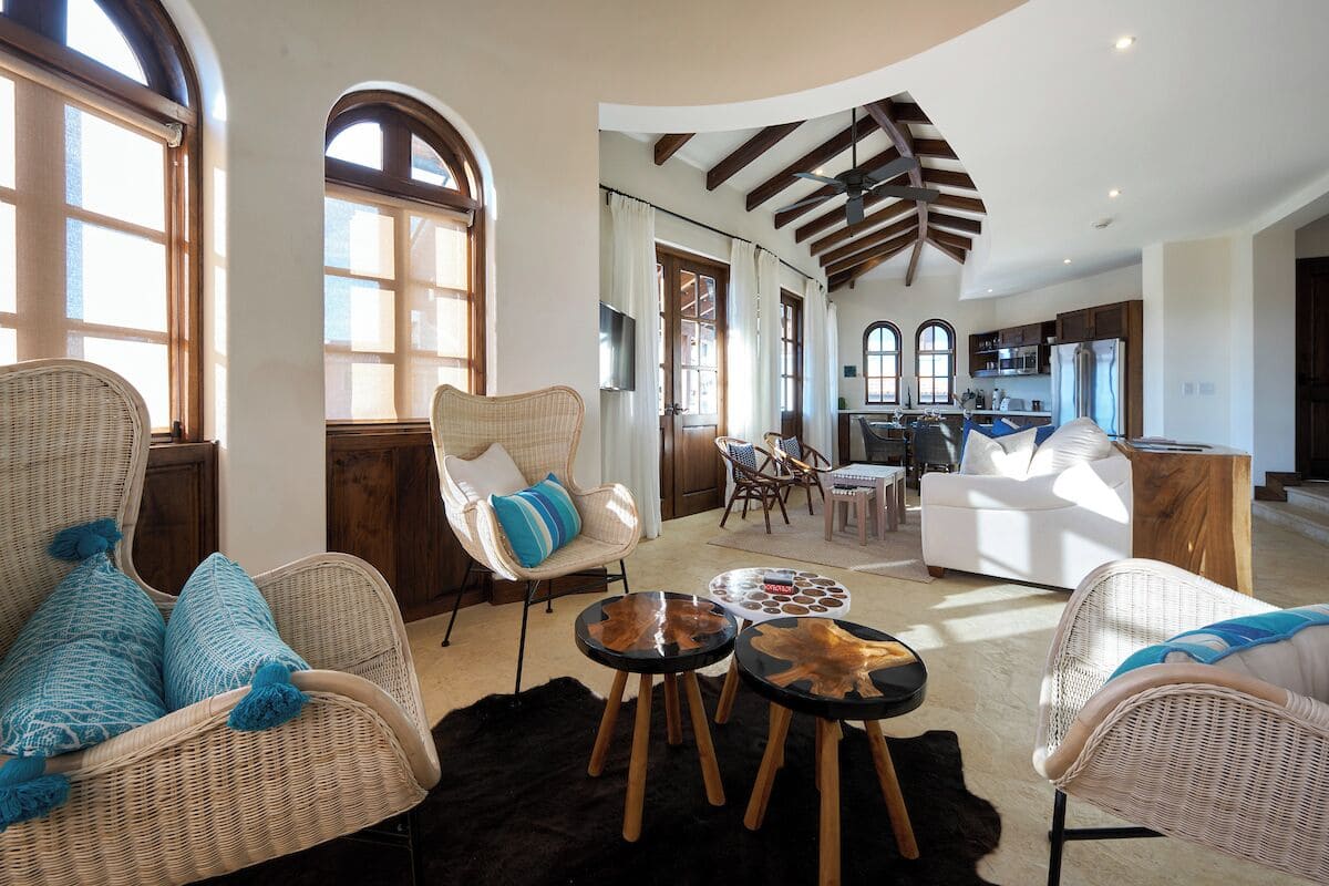 Amplia sala de estar con muebles de mimbre, una mesa de comedor y una cocina al fondo.
