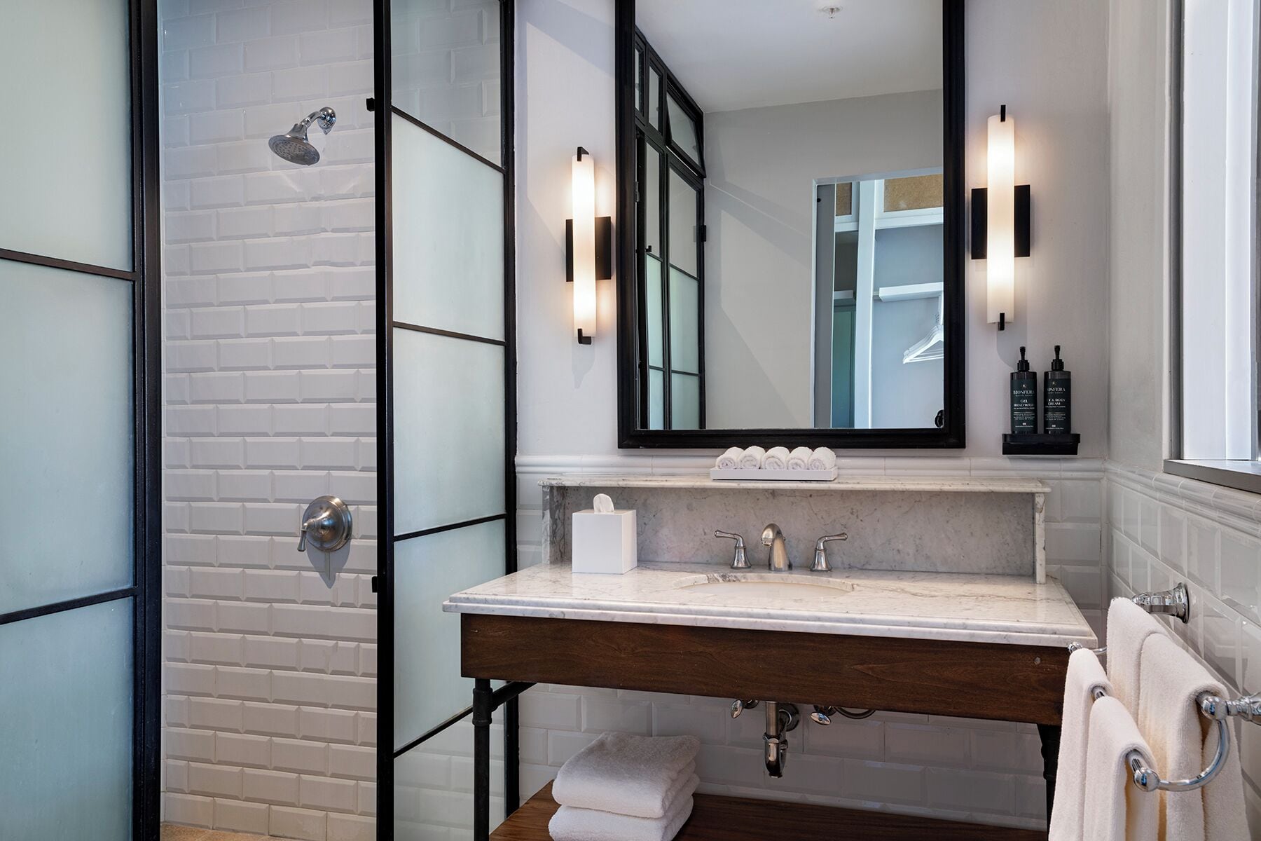 A modern bathroom with a glass shower enclosure, a marble sink, and a large mirror.