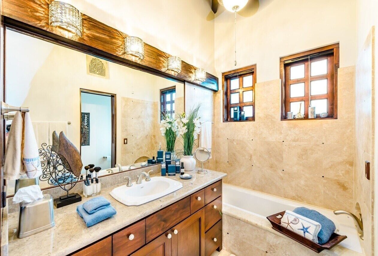 A bathroom with a large mirror, wooden vanity, and a bathtub.