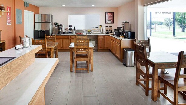 A modern kitchen with wooden cabinets, a stainless steel refrigerator, and a large window offering a view of the outdoors. - Econo Lodge Phillipsburg (Phillipsburg)