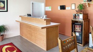 A reception area with a wooden desk, a laptop, a refrigerator stocked with beverages, and a potted plant. - Econo Lodge Phillipsburg (Phillipsburg)