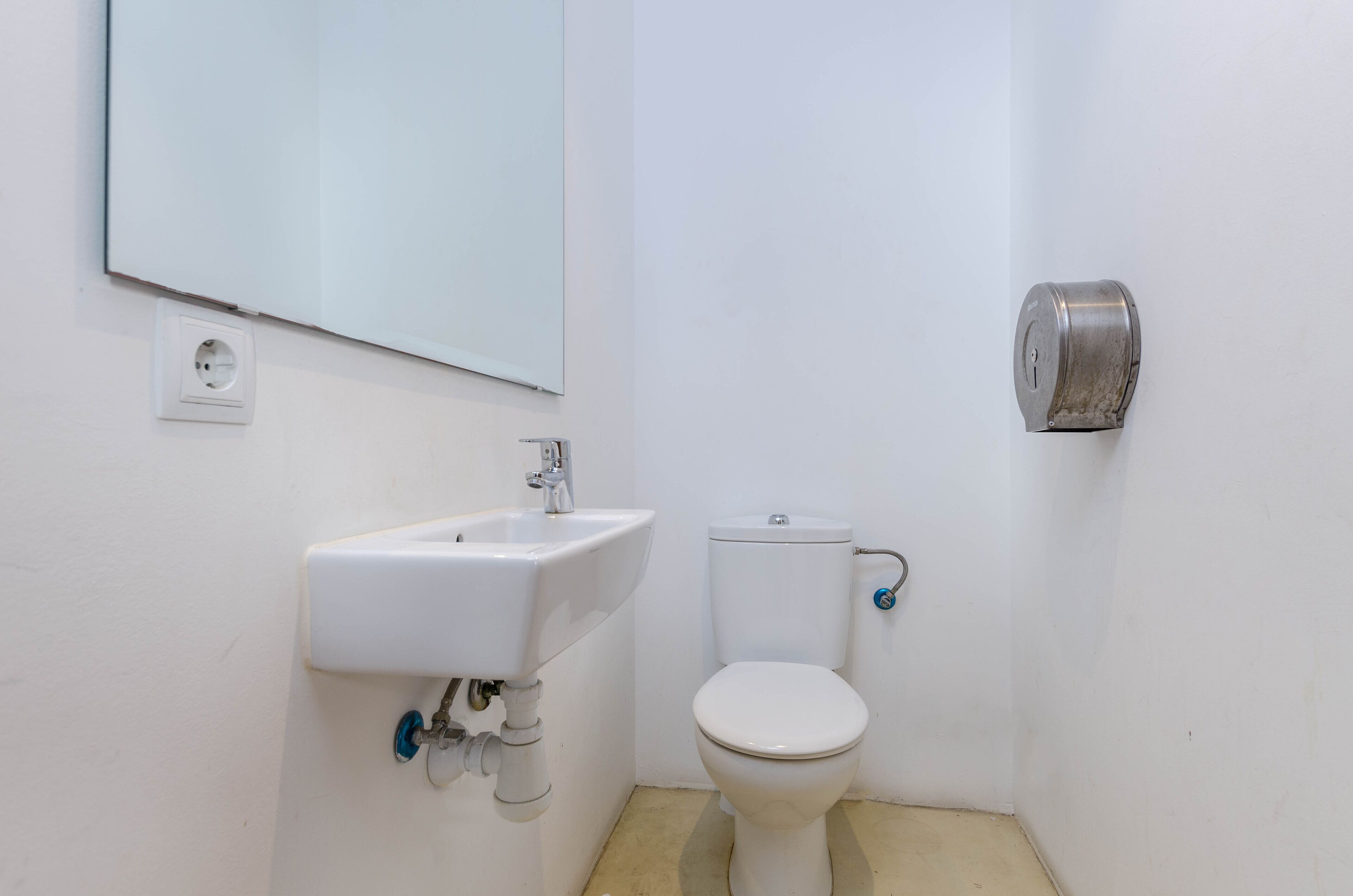 A small, clean bathroom with a white sink, toilet, and a mirror.