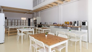 A modern kitchen with white cabinetry, wooden beams, and a mezzanine level. - Urban Hostel Palma Albergue Juvenil (Palma de Mallorca)