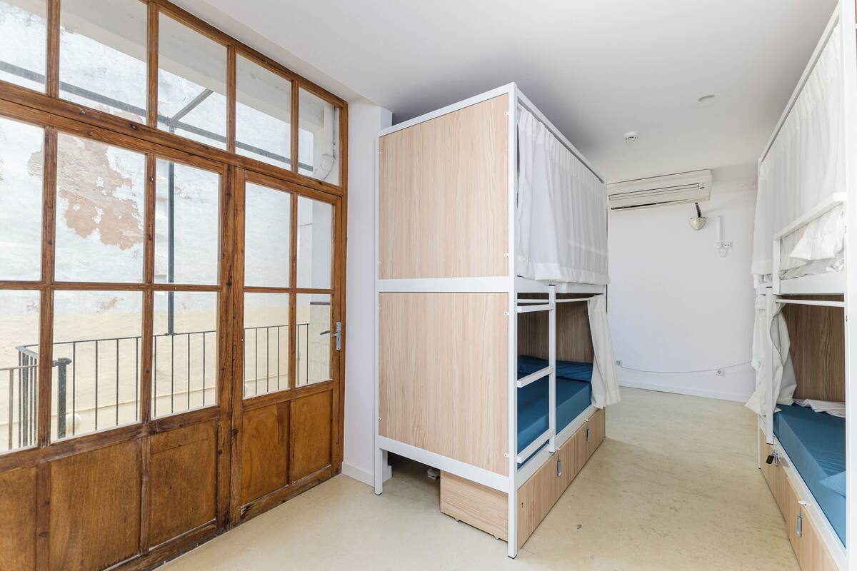 A room with bunk beds, a wooden door, and an air conditioning unit.