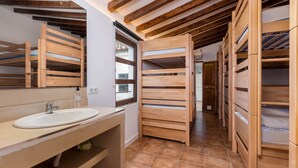 A modern bathroom with wooden bunk beds, a sink, and a window. - Urban Hostel Palma Albergue Juvenil (Palma de Mallorca)