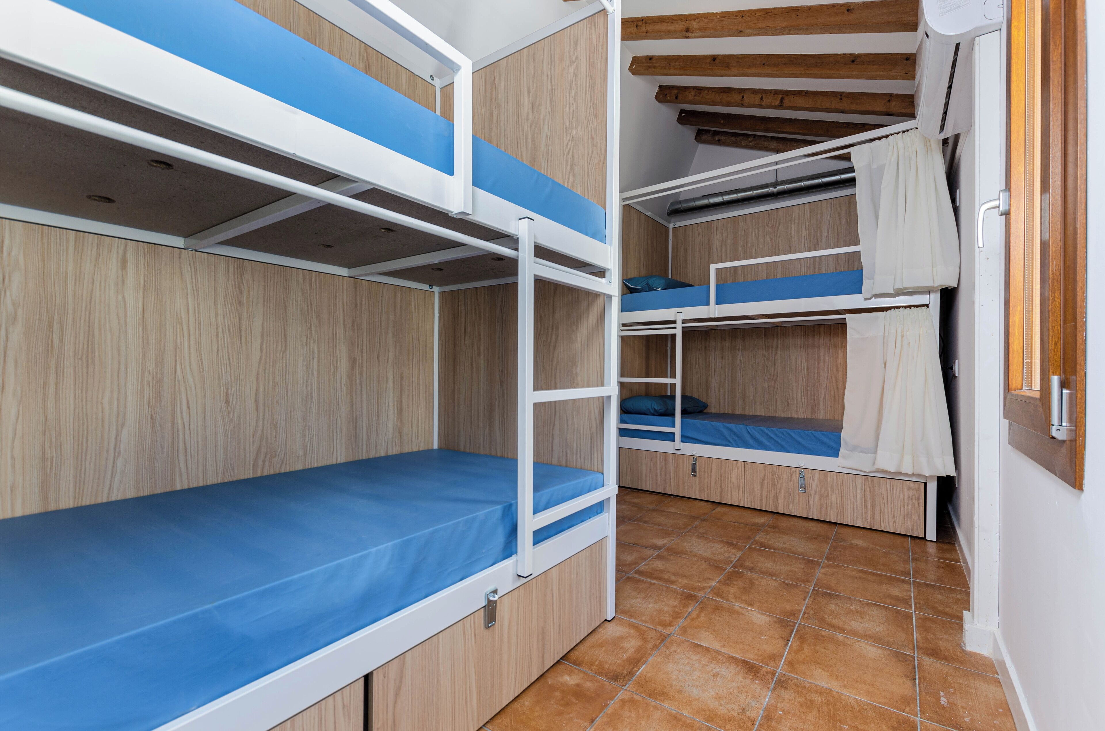 A room with bunk beds, wooden walls, and a tiled floor.