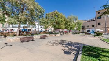 A spacious public square with benches, trees, and a playground.