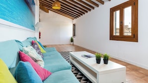 A modern living room with a sofa, a coffee table, and a painting of a beach scene. - Urban Hostel Palma Albergue Juvenil (Palma de Mallorca)