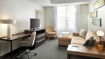 Una habitación de hotel moderna con escritorio, silla, sofá y televisión.