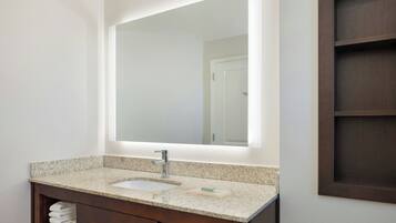 Une salle de bain avec un lavabo à vasque en granit, un grand miroir et un meuble-lavabo en bois.