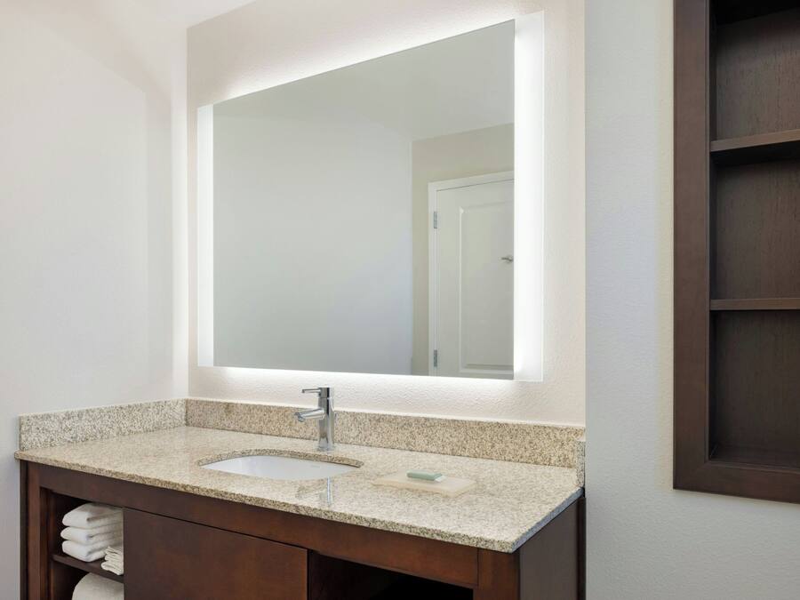 Une salle de bain avec un lavabo à vasque en granit, un grand miroir et un meuble-lavabo en bois.