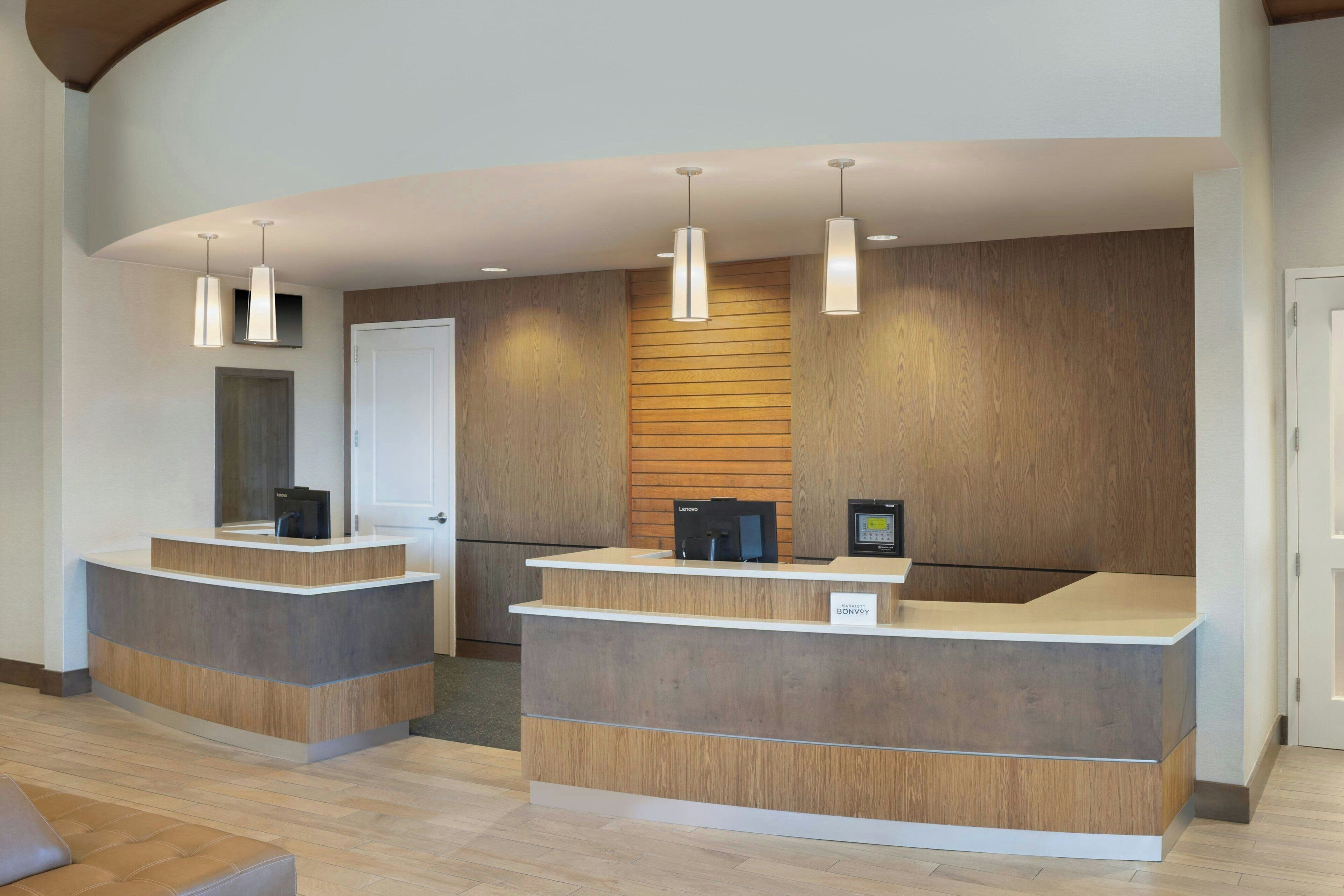 Un área de recepción con dos mostradores, paneles de madera en las paredes e iluminación colgante.