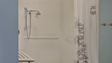 Un espace douche équipé d’un pommeau de douche, d’un pommeau de douche à main et d’un rideau.