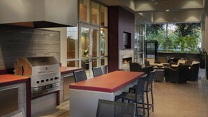 A modern kitchen with a built-in grill, a fireplace, and a dining area with outdoor seating. - Residence Inn by Marriott Orlando Downtown (Orlando)