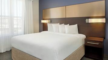 A hotel room with a large bed, a wooden headboard, bedside lamps, and a nightstand.