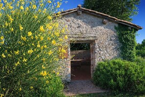 A rustic stone building with a wooden door and a small porch area. - Agriturismo Nerbona (Colle di Val d'Elsa)