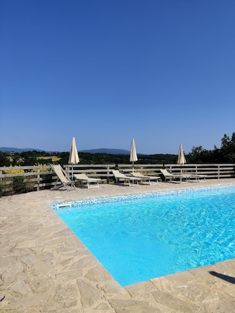 Una piscina al aire libre de temporada, sombrillas