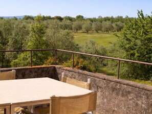 A terrace with a table and chairs, overlooking a lush landscape with trees and a clear sky. - Agriturismo Nerbona (Colle di Val d'Elsa)