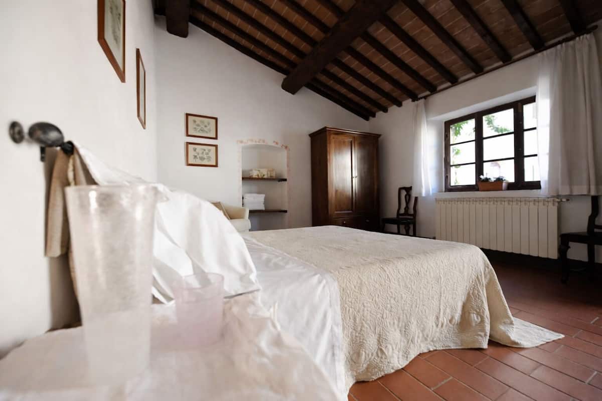Un dormitorio con una cama grande, un armario de madera y una ventana con cortinas.