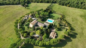An aerial view of a property with a swimming pool, multiple buildings, and a well-maintained lawn.
