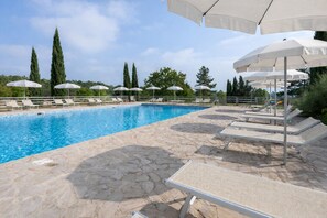A swimming pool with stone flooring and white umbrellas. - Agriturismo Nerbona (Colle di Val d'Elsa)