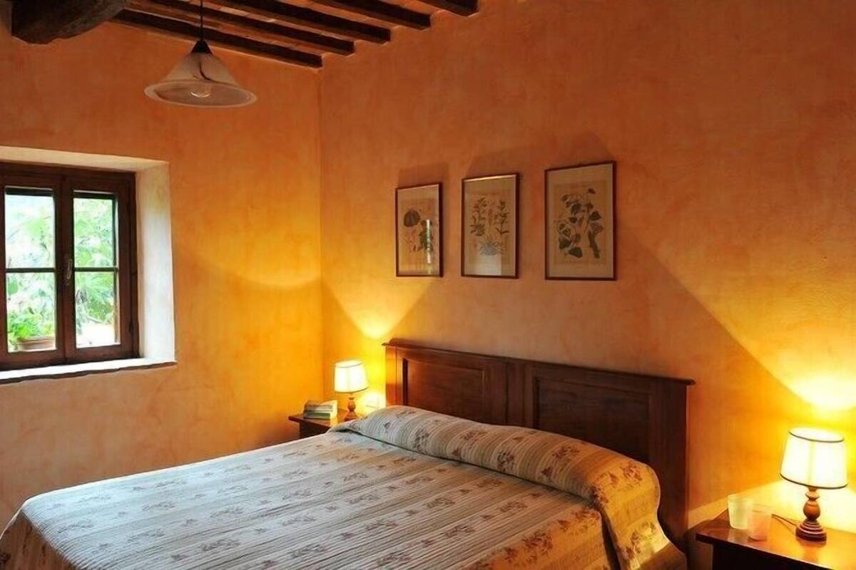 Un dormitorio con una cama, una ventana y tres cuadros en la pared.